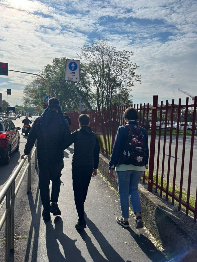 Una serie di foto ci mostrano i giovani studenti della classe seconda A CAT dell'Istituto Cardano muoversi fuori dalla scuola in strada, fino a piazzale Lampugnano, bendati e accompagnati da un compagno di classe. In queste foto è evidente come alcune scelte di design non siamo inclusive e si basino solamente su una scelta di tipo estetico. Nella terzultima foto vediamo in ragazzi nella stazione della metro M1 di Lampugnano, che cercano di capire dove si trovi la linea gialla grazie alla texture del pavimento.