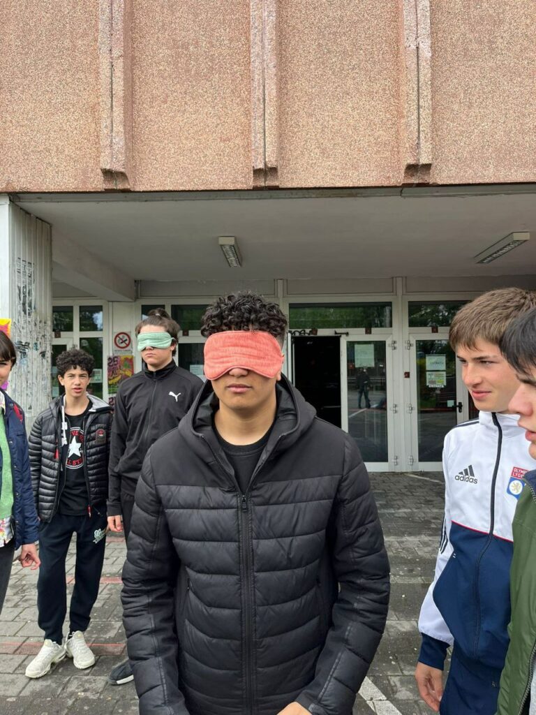 Un ragazzo bendato sta per essere accompagnato dai compagni fuori dall'Istituto Cardano.